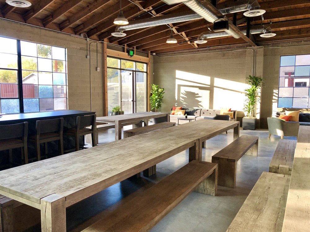 Long picnic tables, couches, and colorful windows inside T.F. Brewing