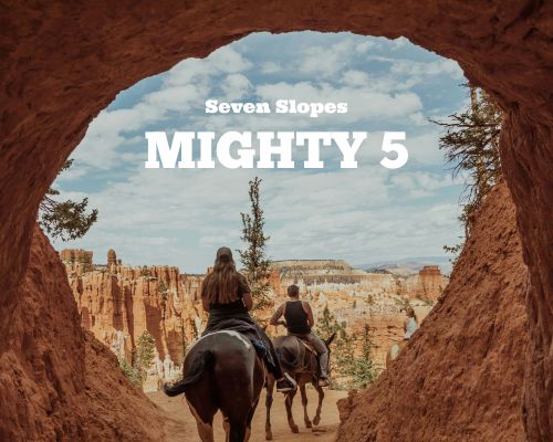 View from a desert arch with two horse back riders riding into the desert.